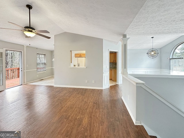 unfurnished living room featuring hardwood / wood-style floors, ceiling fan with notable chandelier, a textured ceiling, and vaulted ceiling