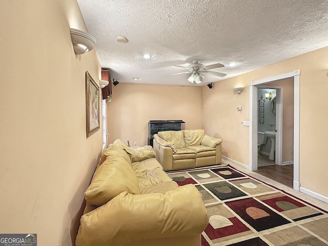 living room featuring hardwood / wood-style flooring, ceiling fan, and a textured ceiling