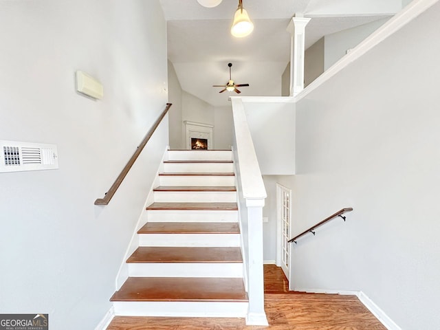 stairway with hardwood / wood-style floors, ceiling fan, and a high ceiling