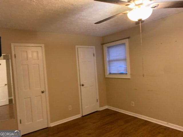 unfurnished bedroom featuring dark hardwood / wood-style flooring, a textured ceiling, and ceiling fan