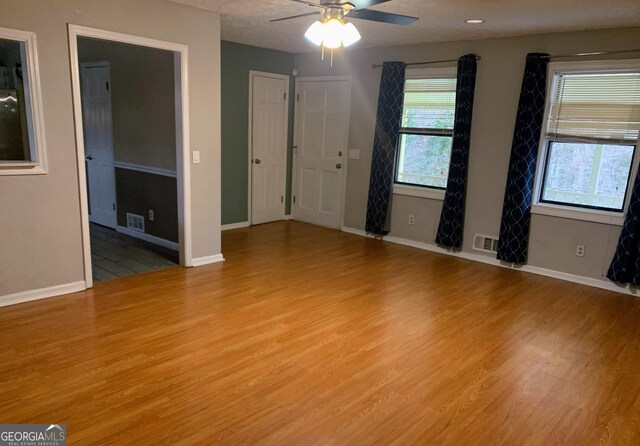 empty room featuring ceiling fan, a healthy amount of sunlight, and light hardwood / wood-style floors