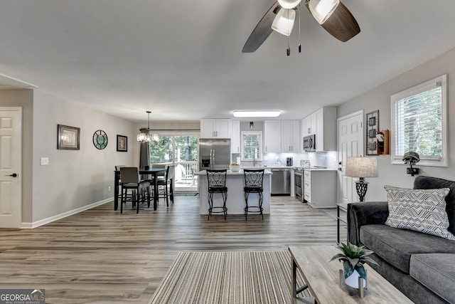 living room with ceiling fan with notable chandelier and hardwood / wood-style flooring