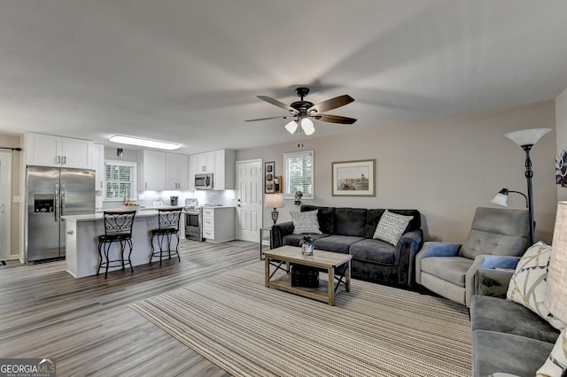 living room with ceiling fan and light wood-type flooring