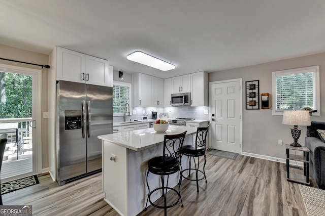 kitchen featuring a breakfast bar, white cabinets, light hardwood / wood-style floors, a kitchen island, and stainless steel appliances