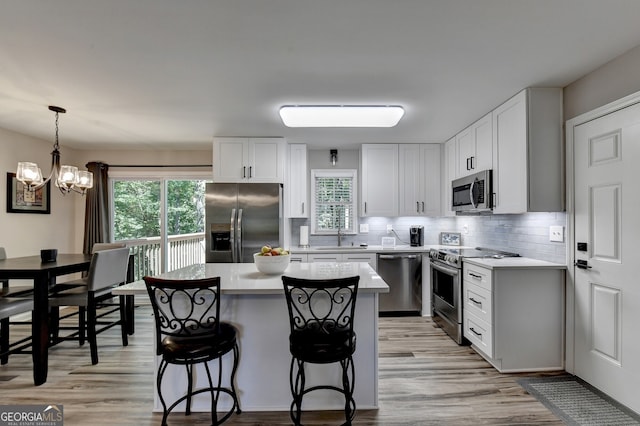 kitchen with decorative backsplash, stainless steel appliances, sink, a center island, and white cabinetry