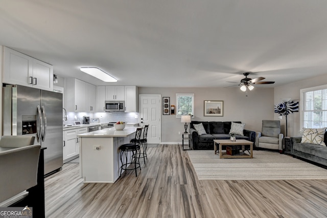 kitchen featuring a center island, white cabinets, a kitchen breakfast bar, ceiling fan, and stainless steel appliances