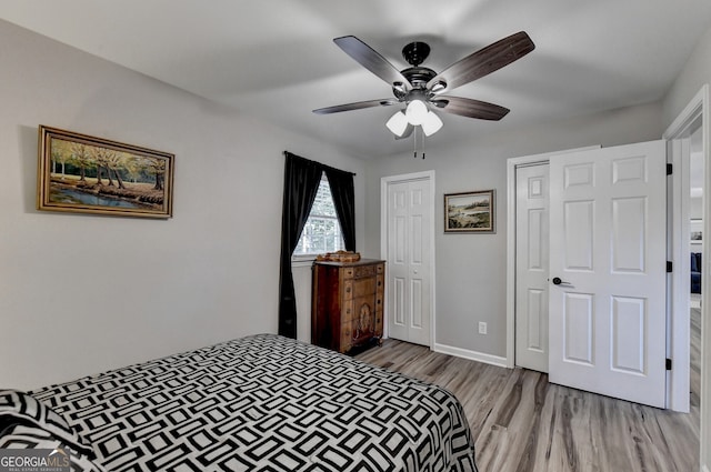 bedroom featuring ceiling fan, light wood-type flooring, and multiple closets