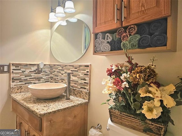 full bathroom featuring vanity, combined bath / shower with glass door, backsplash, and toilet