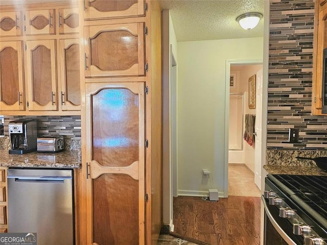 kitchen with light stone counters, backsplash, stainless steel appliances, and a textured ceiling