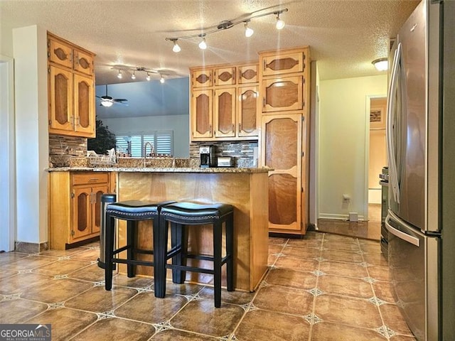 kitchen featuring a wealth of natural light, sink, stainless steel dishwasher, ceiling fan, and light stone countertops