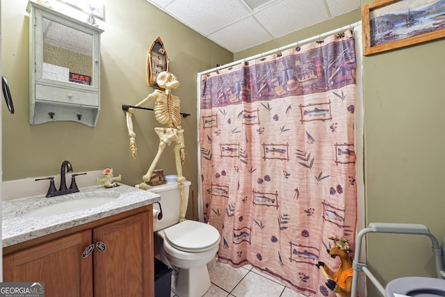 bathroom featuring a drop ceiling, walk in shower, tile patterned floors, toilet, and vanity