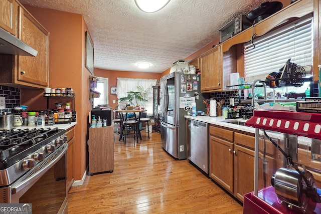 kitchen featuring a textured ceiling, decorative backsplash, stainless steel appliances, and extractor fan