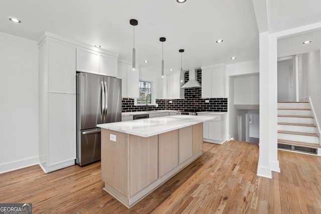 kitchen with pendant lighting, light wood-type flooring, appliances with stainless steel finishes, a kitchen island, and white cabinetry