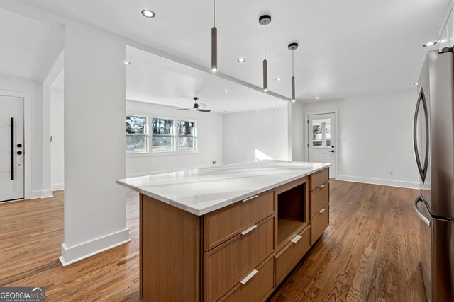 kitchen featuring pendant lighting, plenty of natural light, stainless steel fridge, and a center island