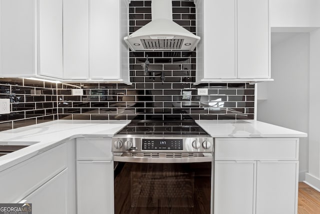 kitchen with light stone countertops, decorative backsplash, stainless steel stove, and white cabinetry