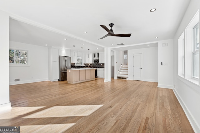 unfurnished living room featuring light hardwood / wood-style floors, ceiling fan, and sink