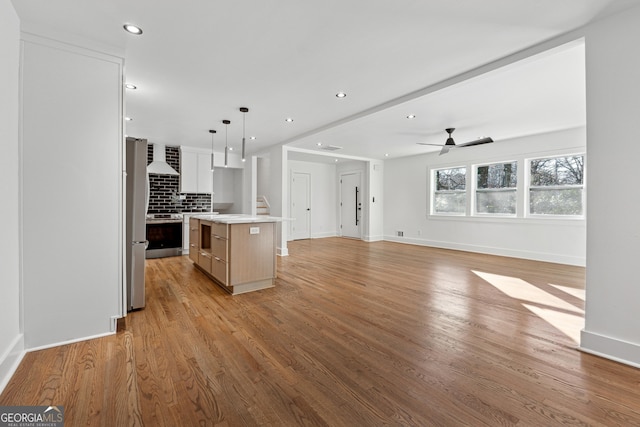 kitchen with a center island, decorative backsplash, appliances with stainless steel finishes, decorative light fixtures, and white cabinetry