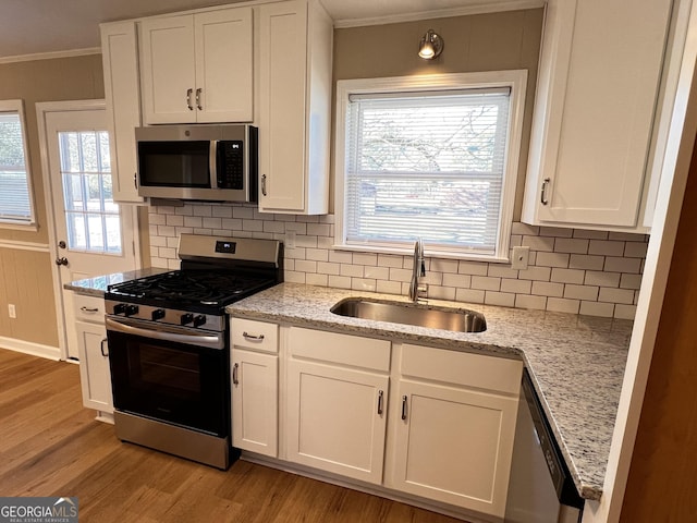 kitchen with sink, stainless steel appliances, light stone counters, backsplash, and white cabinets