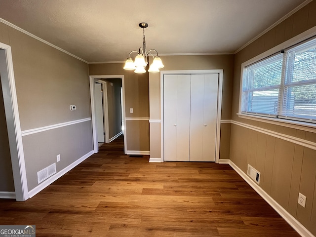 unfurnished bedroom with ornamental molding, a closet, a notable chandelier, and hardwood / wood-style floors