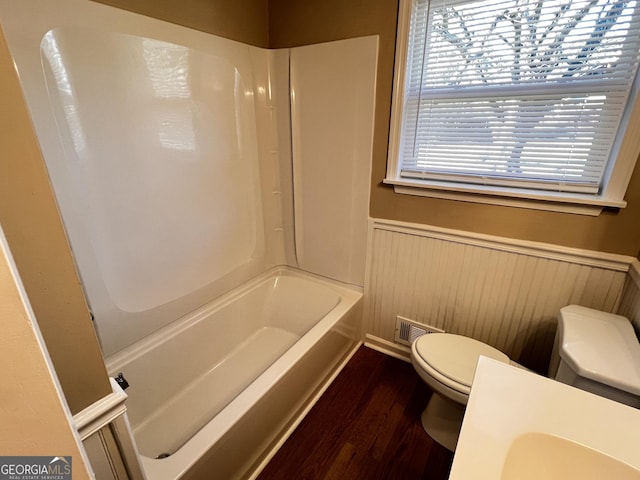 bathroom with shower / washtub combination, hardwood / wood-style floors, and toilet