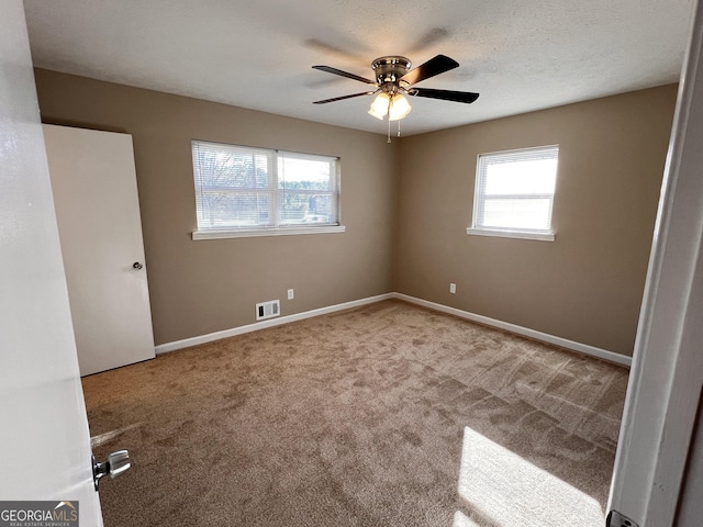 unfurnished room featuring plenty of natural light, ceiling fan, and carpet floors