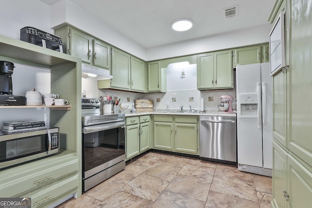 kitchen featuring tasteful backsplash, green cabinets, sink, and stainless steel appliances