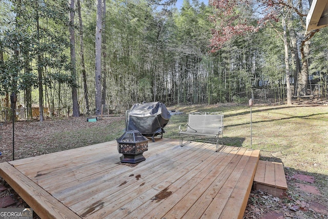 deck with a fire pit, a grill, and a yard