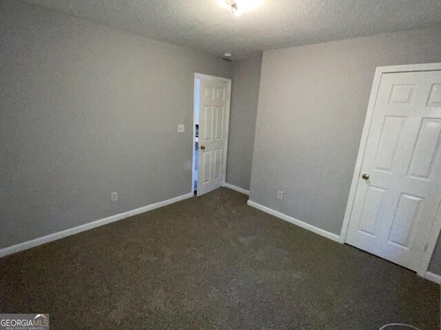 empty room featuring dark colored carpet and a textured ceiling