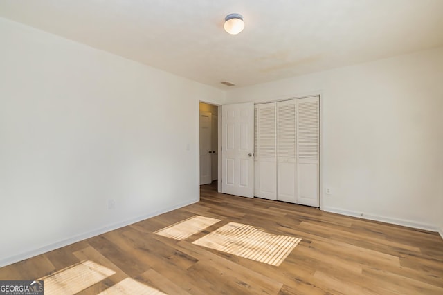 unfurnished bedroom featuring light wood-type flooring and a closet