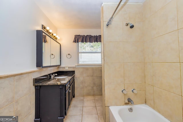 bathroom with tile patterned floors, vanity, tile walls, and tiled shower / bath