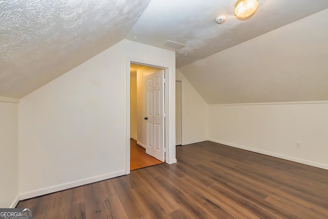 bonus room featuring a textured ceiling, dark hardwood / wood-style floors, and vaulted ceiling