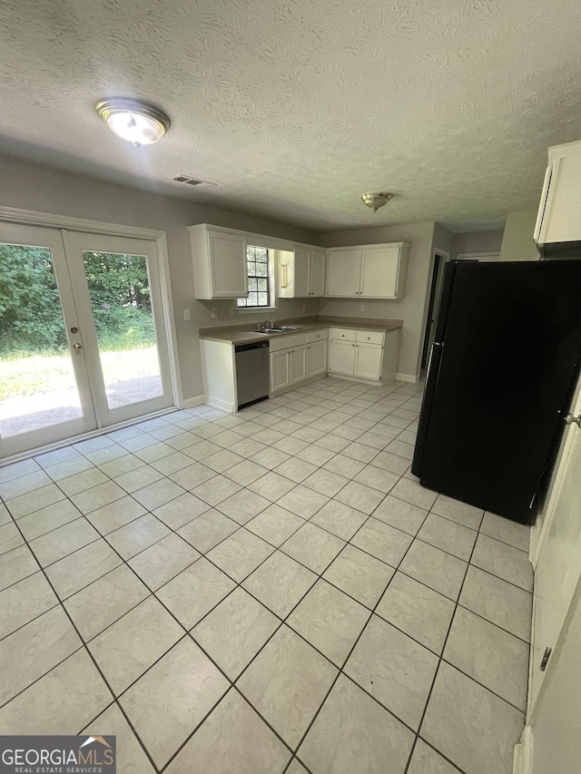 kitchen with black fridge, a textured ceiling, dishwasher, white cabinetry, and light tile patterned flooring