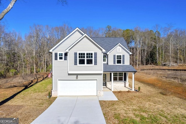 view of property with covered porch, a front yard, and a garage