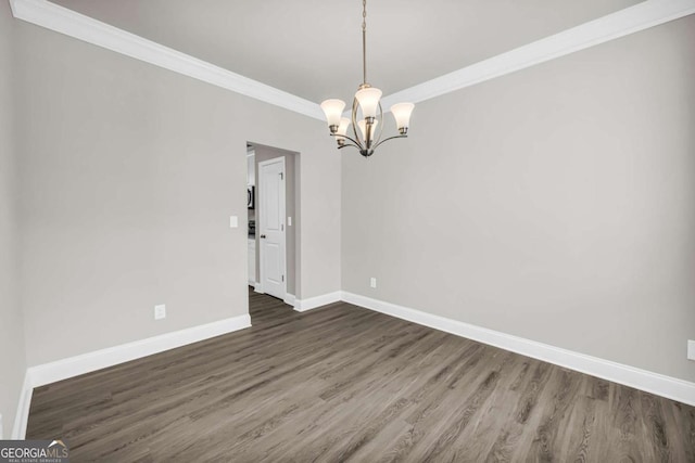 spare room with dark hardwood / wood-style floors, ornamental molding, and a chandelier