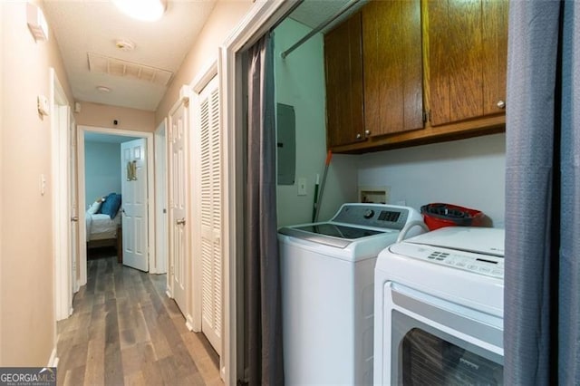 laundry area with cabinets, wood-type flooring, electric panel, and washer and dryer