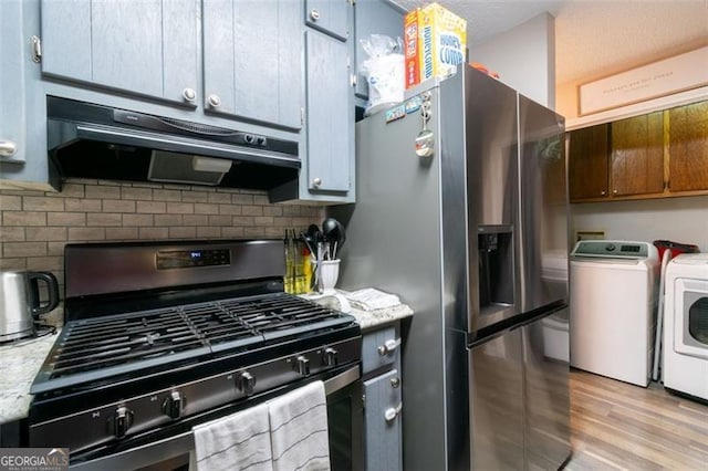 kitchen featuring backsplash, washing machine and dryer, light stone countertops, and stainless steel appliances