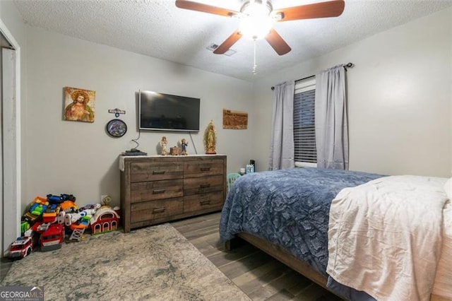 bedroom with a textured ceiling, hardwood / wood-style flooring, and ceiling fan