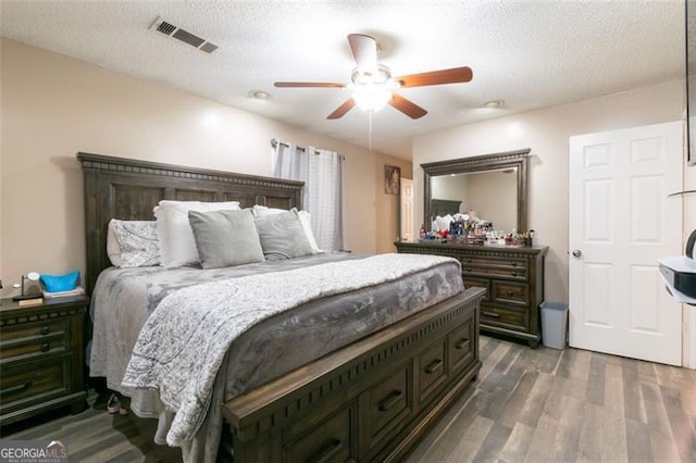 bedroom featuring a textured ceiling, ceiling fan, and dark wood-type flooring