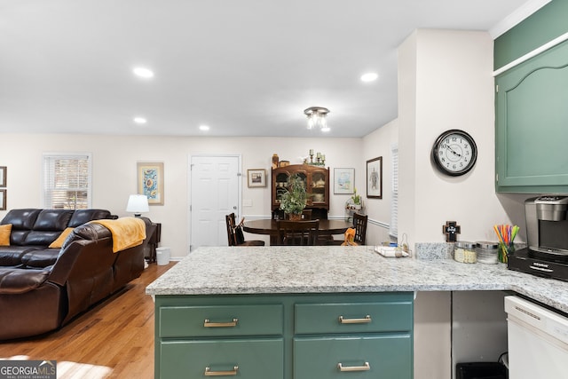 kitchen featuring white dishwasher, green cabinets, light hardwood / wood-style flooring, light stone counters, and kitchen peninsula