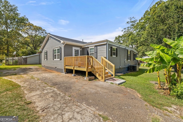 view of front of house with cooling unit, a deck, and a front lawn