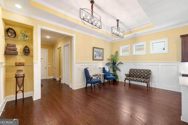 sitting room featuring dark hardwood / wood-style floors, a raised ceiling, crown molding, and an inviting chandelier