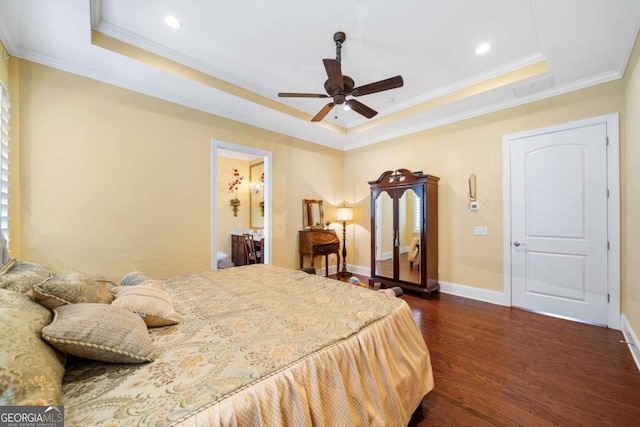 bedroom with ceiling fan, dark hardwood / wood-style flooring, a raised ceiling, and connected bathroom