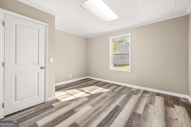 spare room featuring hardwood / wood-style flooring, a drop ceiling, and ornamental molding