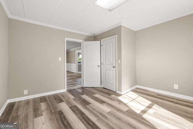 spare room with crown molding and light wood-type flooring