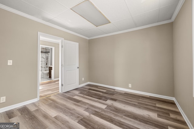 spare room featuring a drop ceiling, ornamental molding, and hardwood / wood-style flooring