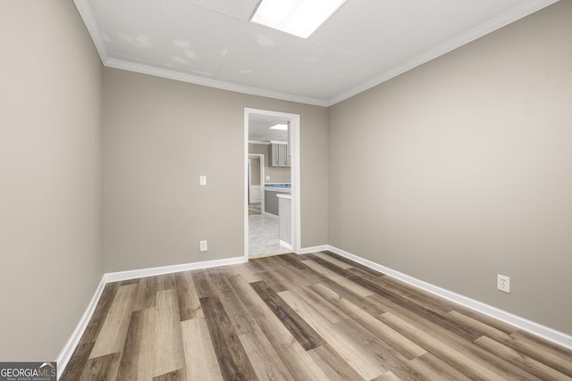 empty room featuring crown molding and light wood-type flooring