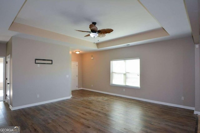 spare room featuring ceiling fan, dark hardwood / wood-style floors, and a tray ceiling