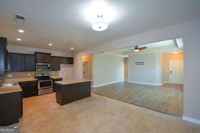 kitchen featuring a center island, sink, ceiling fan, appliances with stainless steel finishes, and tasteful backsplash