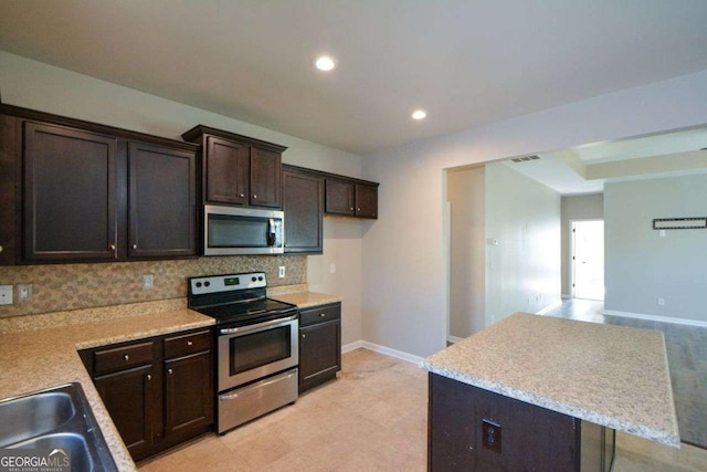 kitchen featuring tasteful backsplash, a center island, stainless steel appliances, and dark brown cabinets