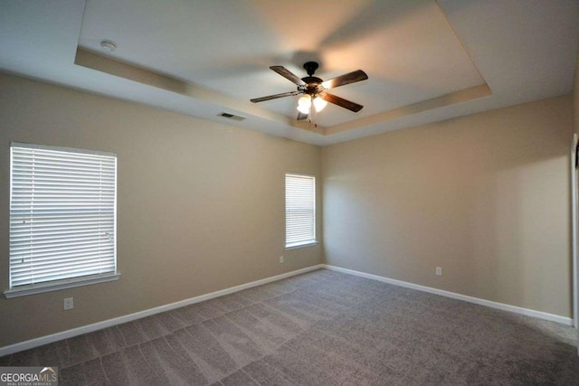 carpeted empty room with ceiling fan and a raised ceiling